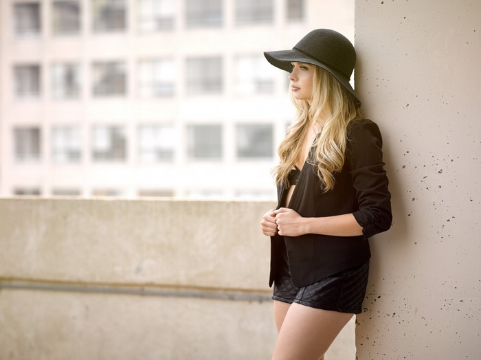 Woman in black hat and jacket posing outdoors
