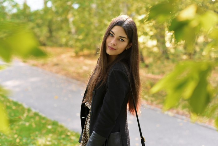 Woman with long brown hair in a black coat outdoors