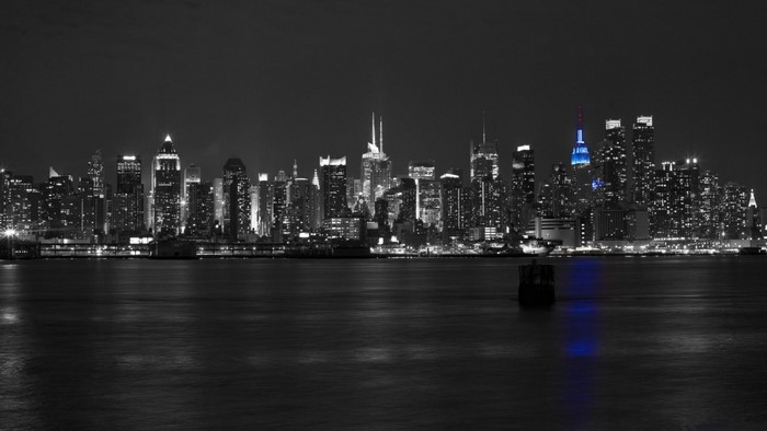 New York City skyline at night with blue illuminated Empire State Building