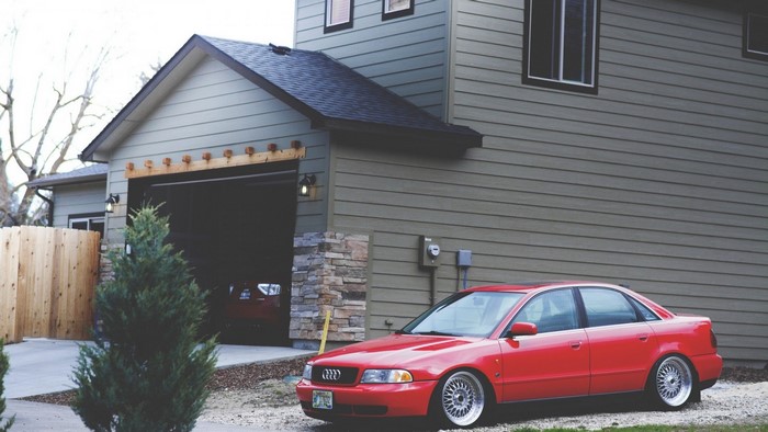 Red Audi A4 Sedan parked in front of a house with garage