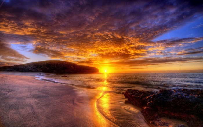 Sunset over a rocky beach with dramatic clouds