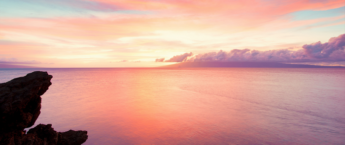 Ocean sunset with rocky cliff and distant island