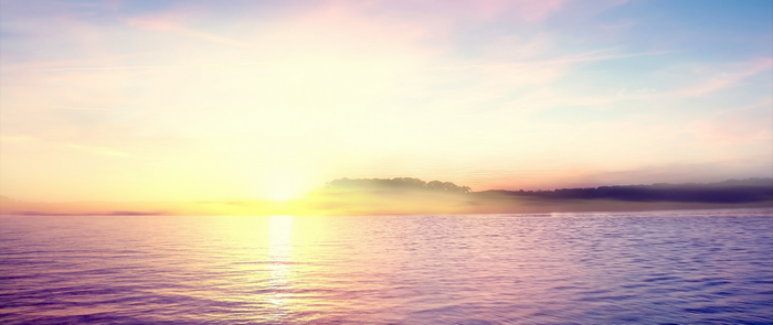 Sunrise over a misty lake with trees on the horizon