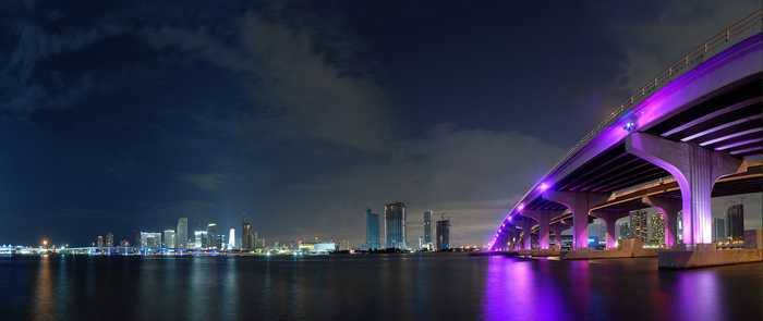 Miami cityscape at night with illuminated bridge and reflections
