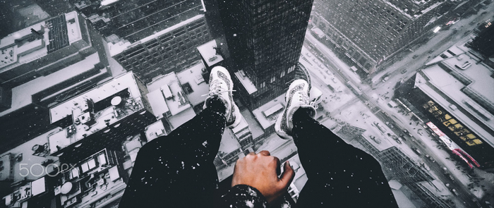 Person sitting on skyscraper edge in snow