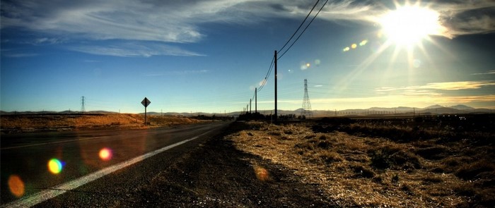 Roadside with power lines and sun