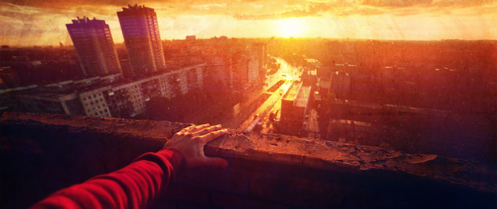 Hand on ledge overlooking city at sunset