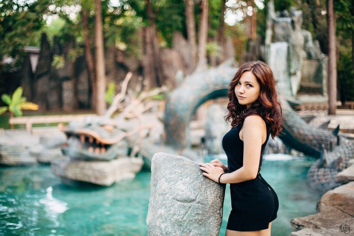 Woman in black dress posing by a dragon fountain