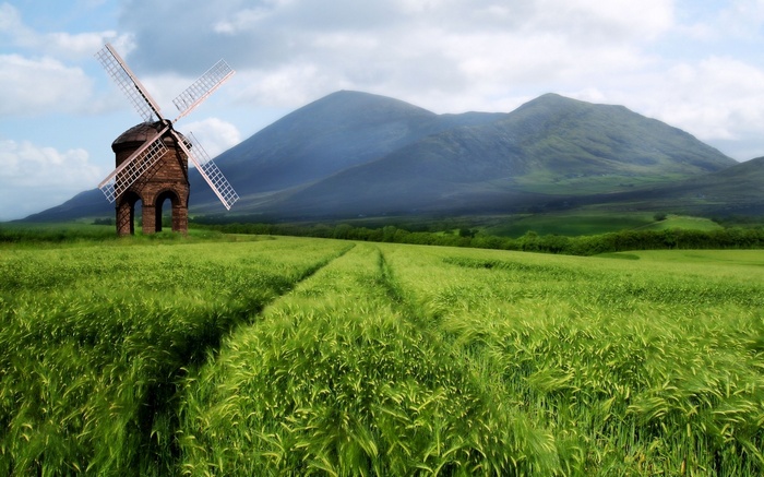 Windmill in a green field with mountains