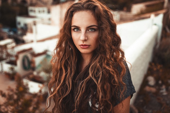 Woman with long curly brown hair and freckles