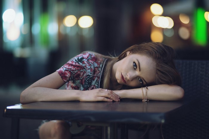 Young woman resting her head on her arm at a table