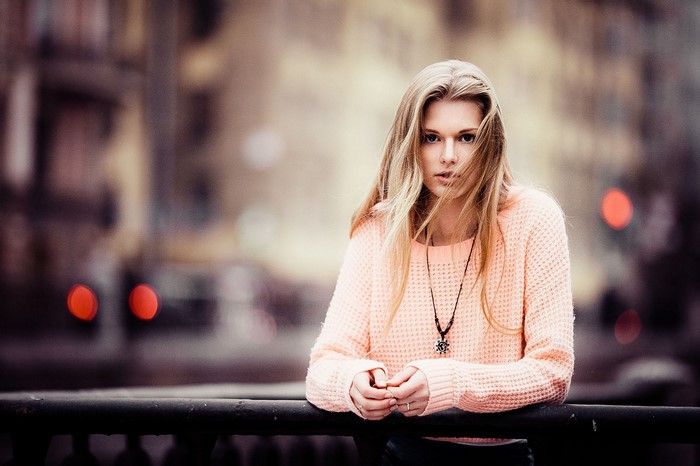 Woman in peach sweater leaning on railing
