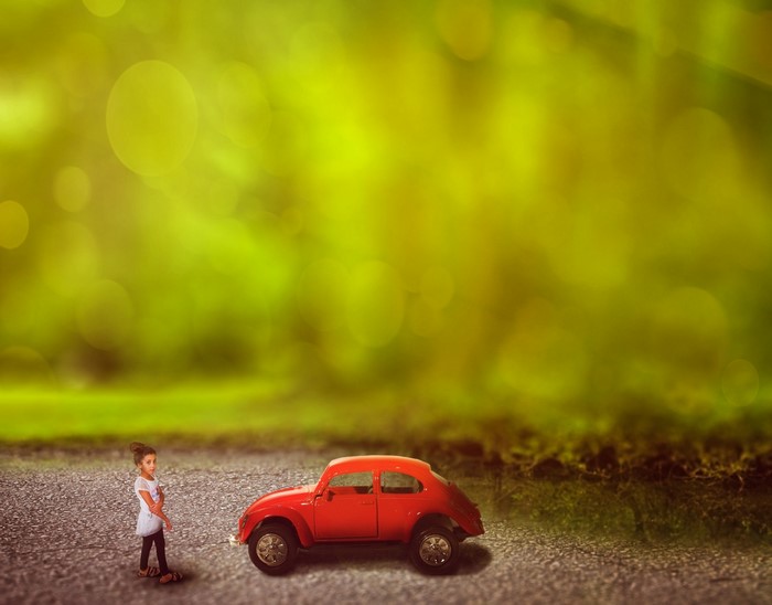 Girl and red toy car in sunlight