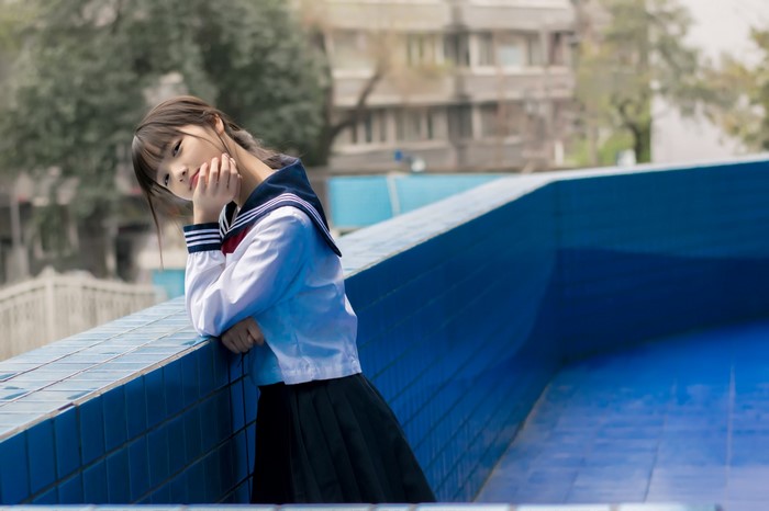 Asian girl in school uniform by a pool