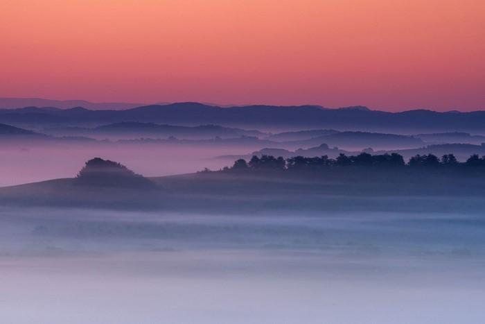 Misty mountain range at sunrise with pink sky