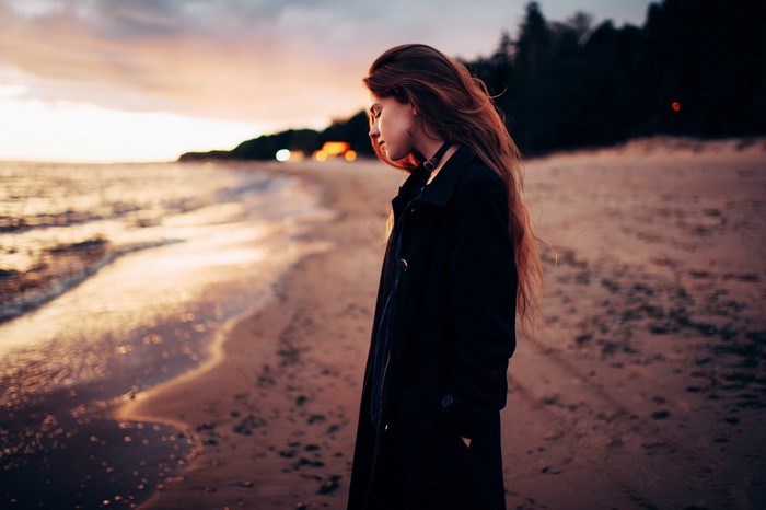 Woman with auburn hair on a beach at sunset