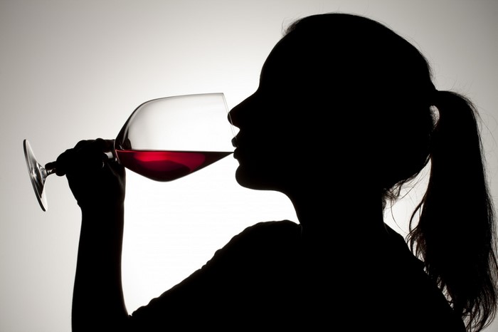 Silhouette of a woman drinking red wine from a large glass