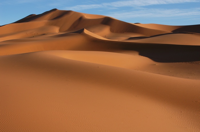 Desert sand dunes under a blue sky