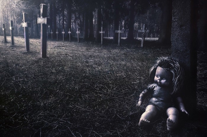 Creepy doll in a dark graveyard at night