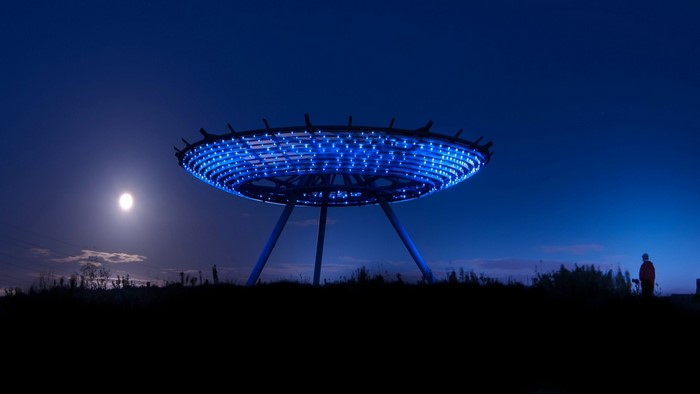 UFO-shaped structure with blue lights at night