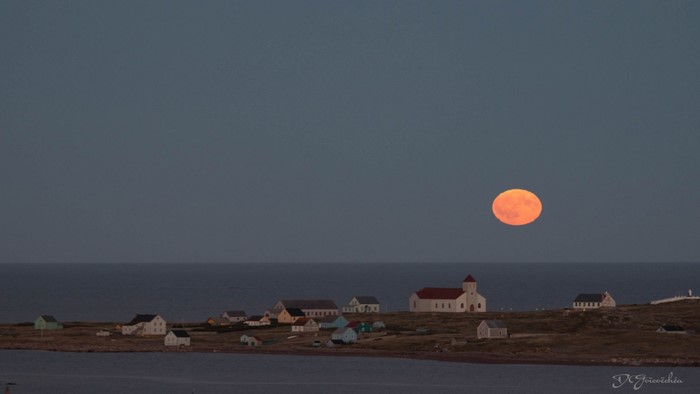 Full moon over coastal village at dusk
