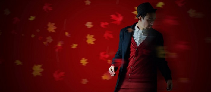 Man in hat and coat on red background with leaves