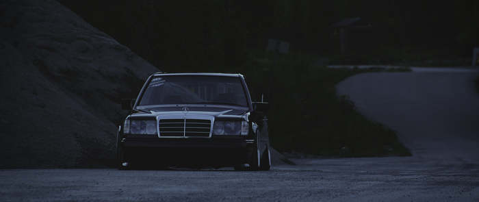 Black Mercedes-Benz E-Class parked on a dirt road at night