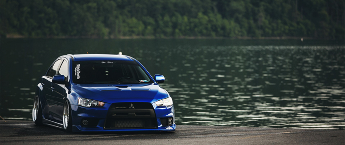 Blue Mitsubishi Lancer EVO parked by a lake