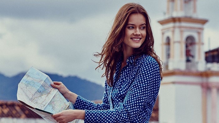 Woman holding a map with a building in the background