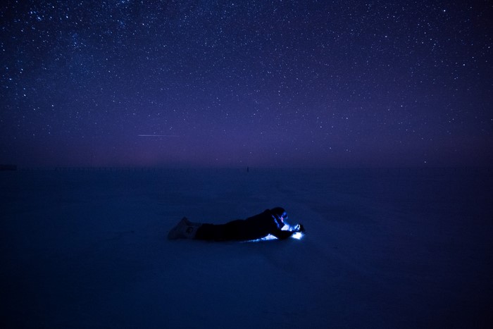 Person lying on snow under starry night sky