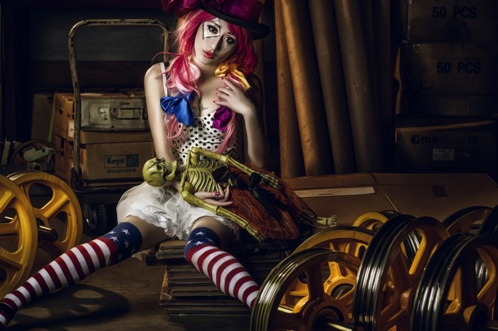 Woman in clown costume holding a skeleton