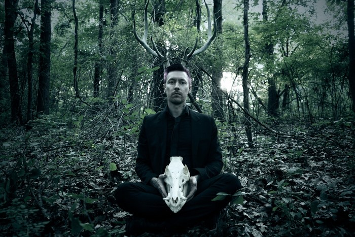 Man with deer antlers and skull in forest