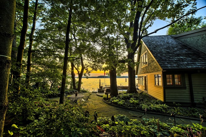 House by the lake at sunset with trees and garden