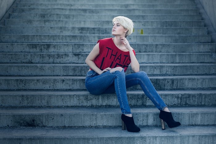 Woman in red top and jeans sitting on stairs