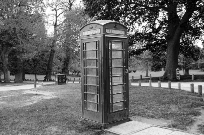 Black and white photo of a telephone booth in a park