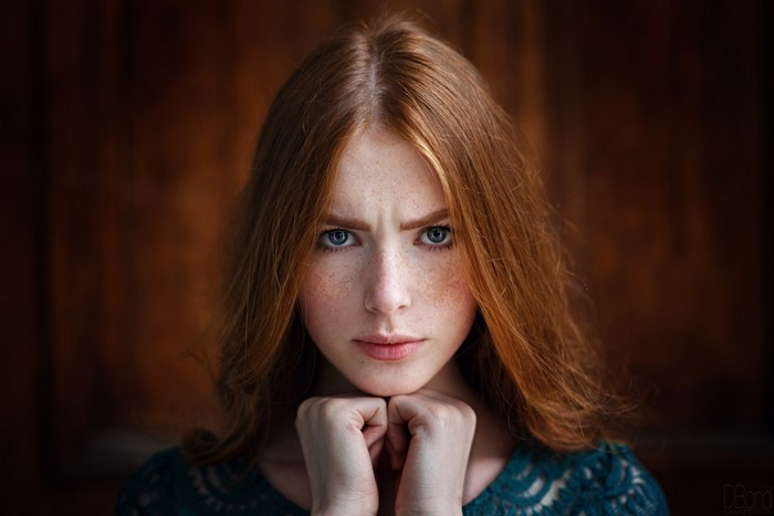 Young woman with red hair and freckles looking at viewer