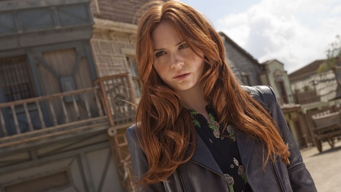 Karen Gillan with long red hair in a leather jacket