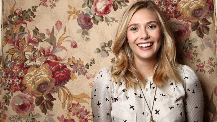 Elizabeth Olsen posing in front of floral wallpaper