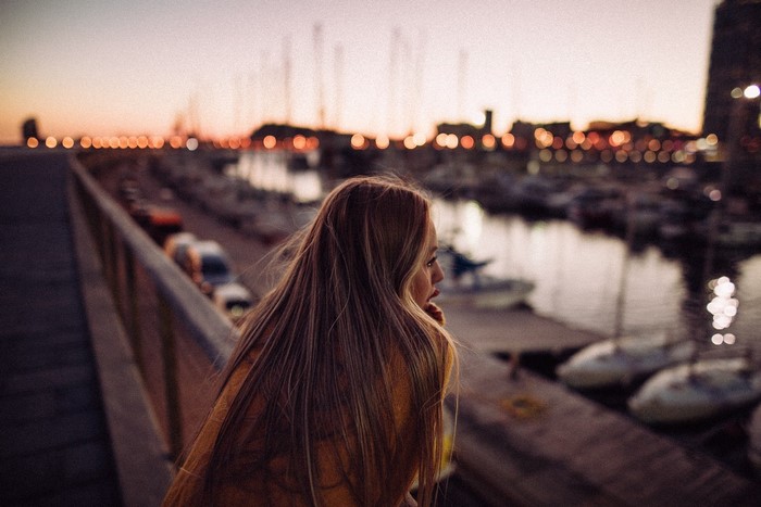 Woman looking out over a harbor at dusk