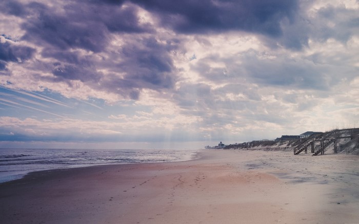 Beach with sand dunes and ocean under cloudy sky