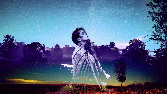 Woman wrapped in a blanket under a starry sky