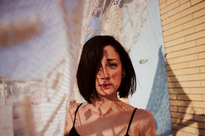 Woman with short dark hair and lace shadow on face