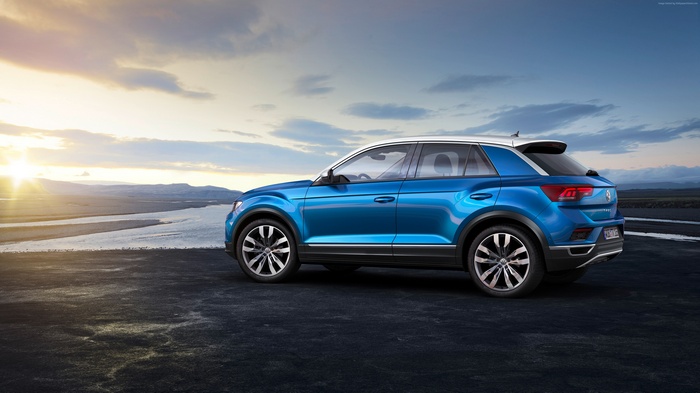 Blue Volkswagen T-Roc parked by a body of water at sunset