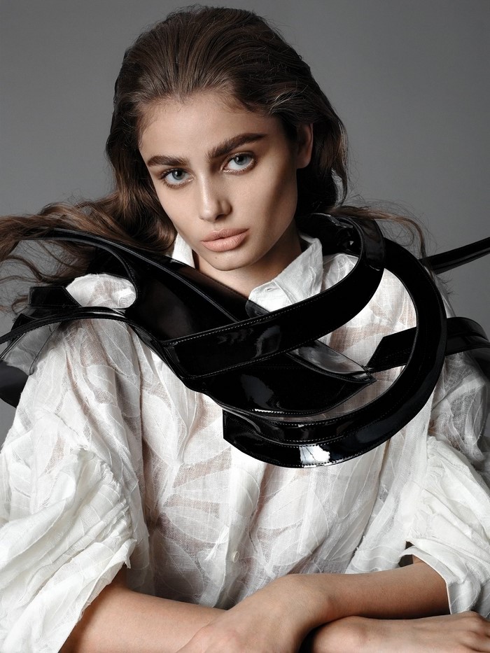 Woman with dark hair wearing a white shirt and black accessory