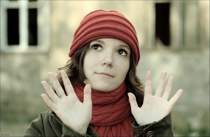 Young woman wearing a red hat and scarf looking up