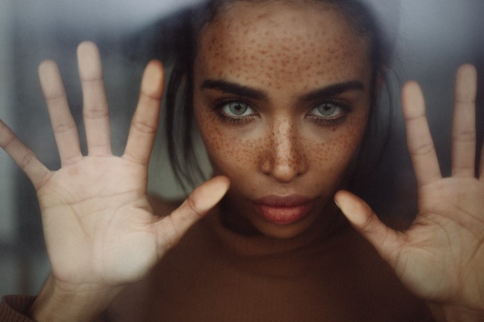 Woman with freckles looking through glass
