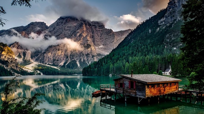 Wooden boathouse on a lake with mountains and forest