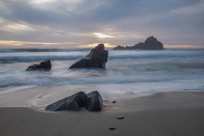 Rocks in the ocean at sunset with waves