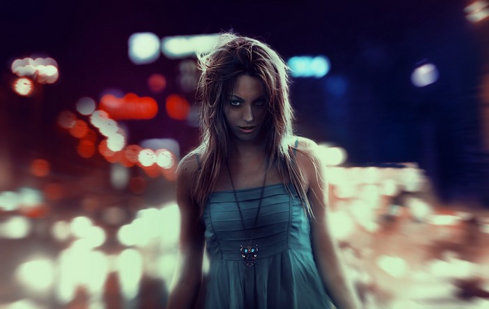 Woman in a blue dress with owl necklace at night