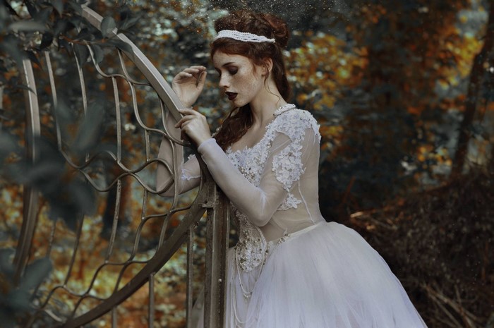 Woman in white dress leaning on a gate
